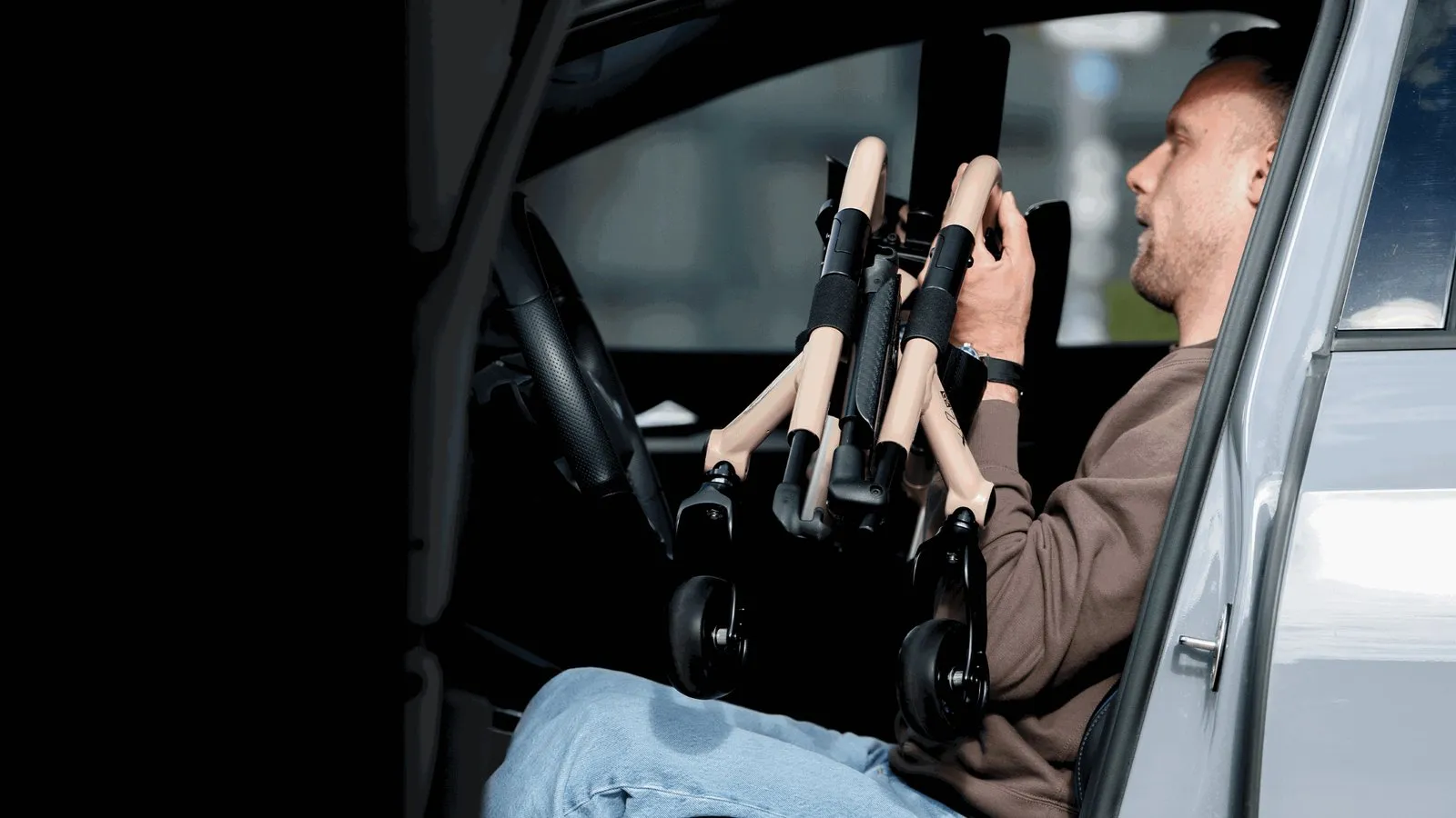 Un hombre sentado en un coche mete la silla Quickie QS7 X plegada por delante